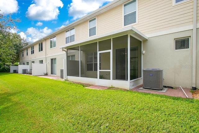 rear view of property featuring a sunroom, central air condition unit, and a lawn