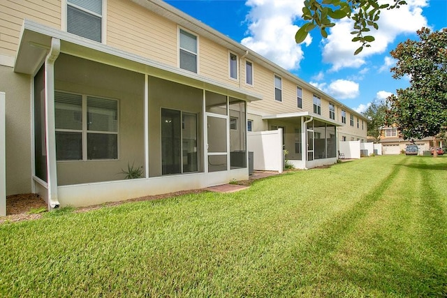 back of property featuring a sunroom and a lawn