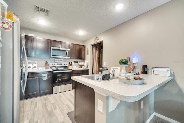 kitchen with stainless steel appliances, a textured ceiling, kitchen peninsula, and a breakfast bar