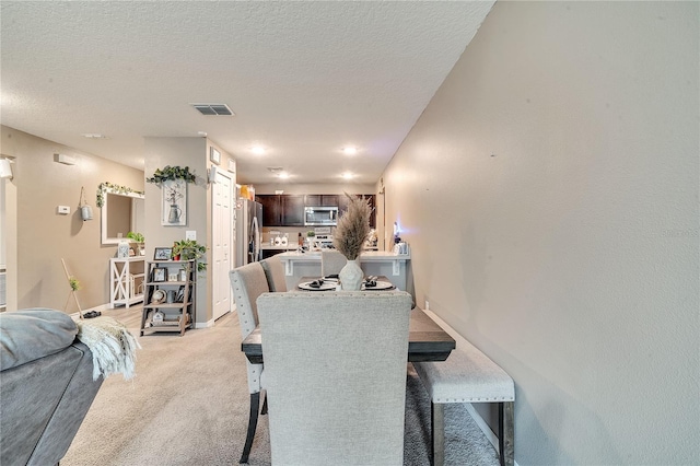 carpeted dining space with a textured ceiling