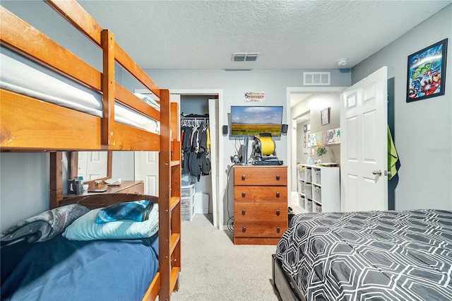 carpeted bedroom with a textured ceiling, a walk in closet, and a closet