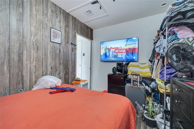 bedroom featuring a textured ceiling and wooden walls