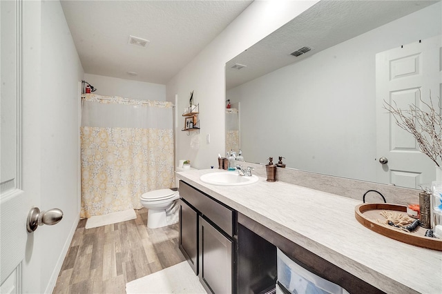 bathroom with a textured ceiling, a shower with shower curtain, vanity, wood-type flooring, and toilet