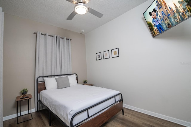 bedroom with hardwood / wood-style floors, ceiling fan, and a textured ceiling