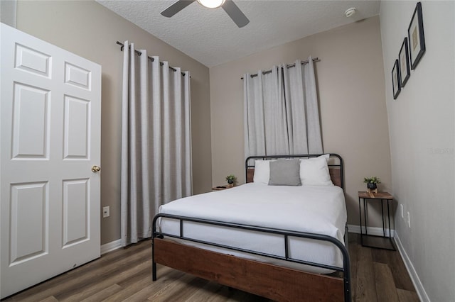 bedroom with a textured ceiling, ceiling fan, and dark hardwood / wood-style flooring