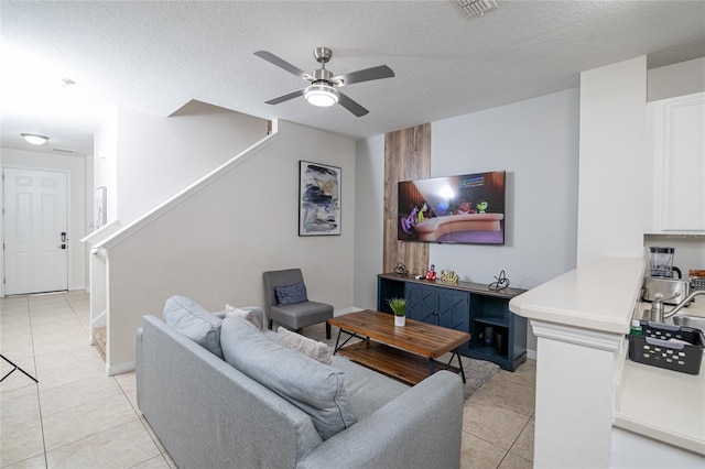 living room featuring light tile patterned flooring, ceiling fan, and a textured ceiling