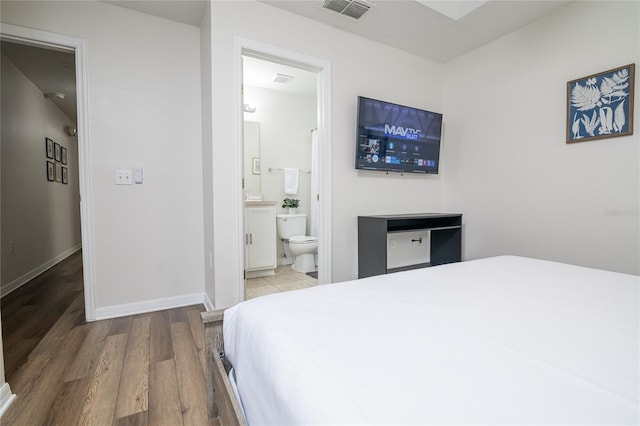 bedroom with ensuite bathroom and hardwood / wood-style floors