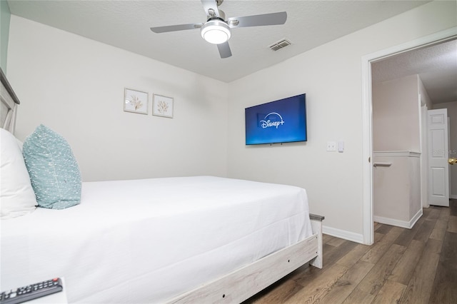 bedroom with a textured ceiling, ceiling fan, and wood-type flooring