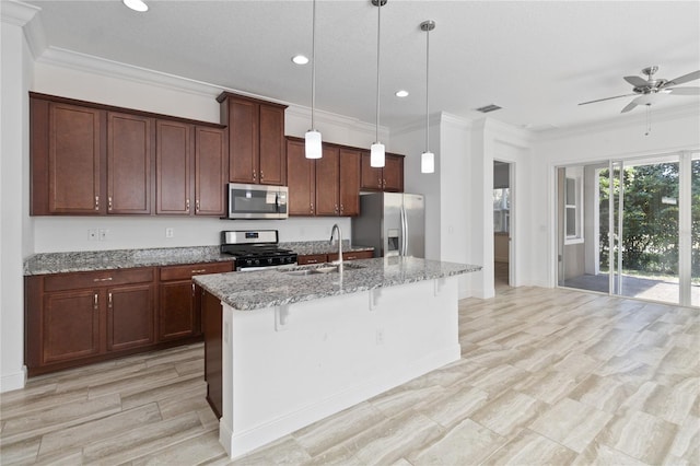 kitchen with appliances with stainless steel finishes, pendant lighting, an island with sink, sink, and light stone counters