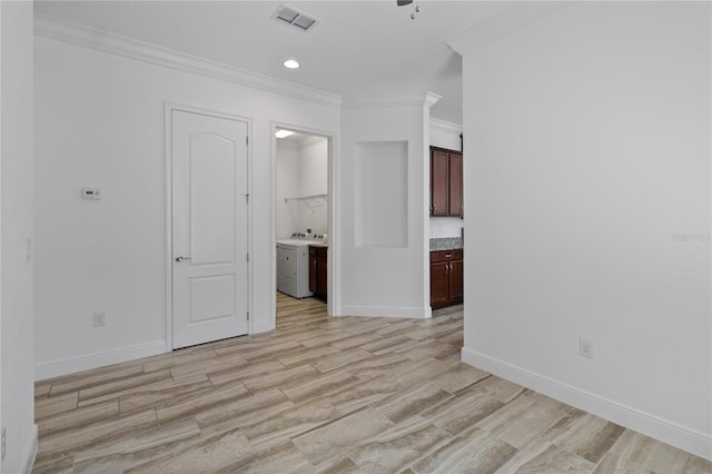 empty room featuring ornamental molding, washer / dryer, and light hardwood / wood-style flooring