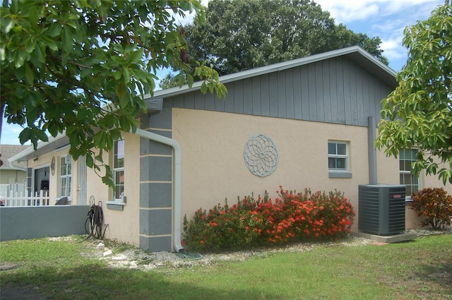 view of side of home featuring a yard and central AC unit