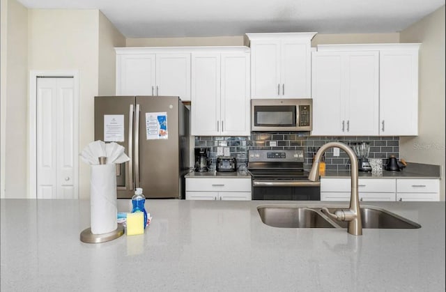 kitchen featuring appliances with stainless steel finishes, white cabinets, tasteful backsplash, and sink