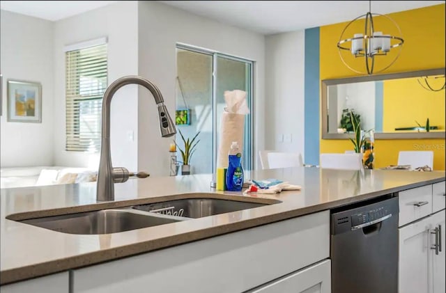 kitchen with white cabinetry, dishwashing machine, a chandelier, hanging light fixtures, and sink