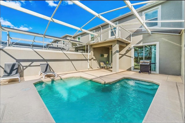 view of swimming pool featuring area for grilling, a patio area, and glass enclosure