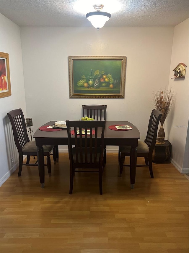 dining space featuring wood-type flooring and a textured ceiling