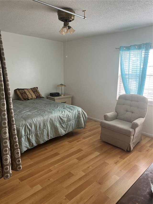 bedroom with light hardwood / wood-style floors, a textured ceiling, and ceiling fan