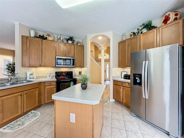 kitchen featuring light tile patterned floors, sink, stainless steel appliances, and a kitchen island