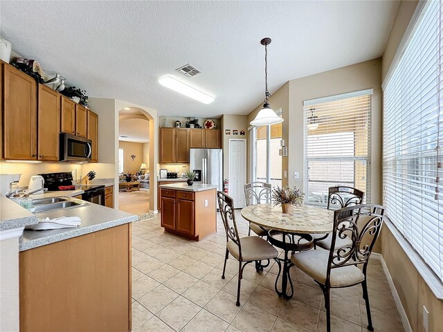 kitchen featuring a kitchen island, light tile patterned floors, pendant lighting, and stainless steel appliances