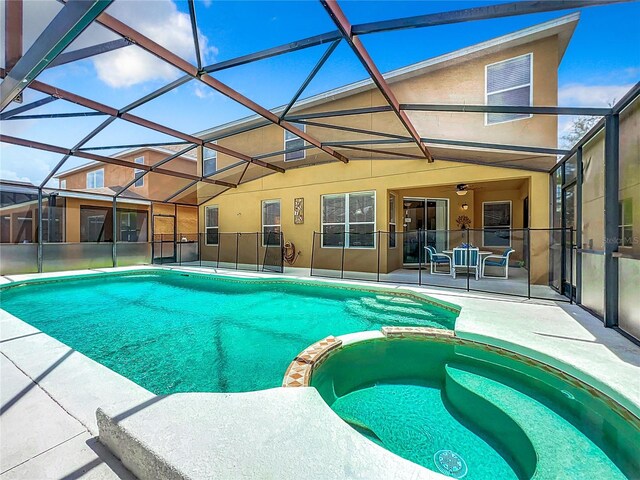 view of swimming pool featuring ceiling fan, glass enclosure, an in ground hot tub, and a patio