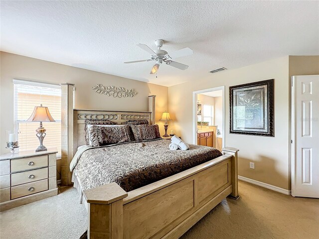 bedroom with light colored carpet, connected bathroom, a textured ceiling, and ceiling fan