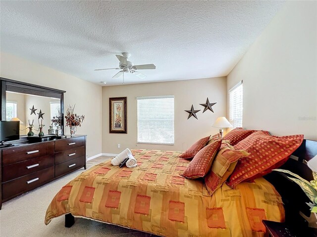 carpeted bedroom featuring ceiling fan and a textured ceiling