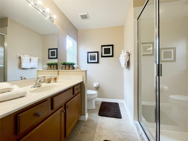 bathroom featuring vanity, tile patterned floors, a textured ceiling, toilet, and a shower with door