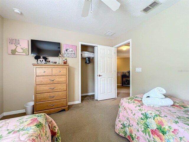 bedroom with ceiling fan, a closet, a textured ceiling, and light colored carpet