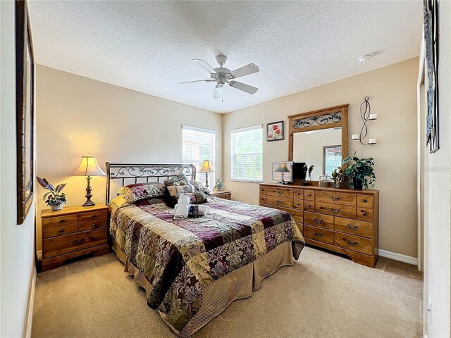 carpeted bedroom with ceiling fan and a textured ceiling