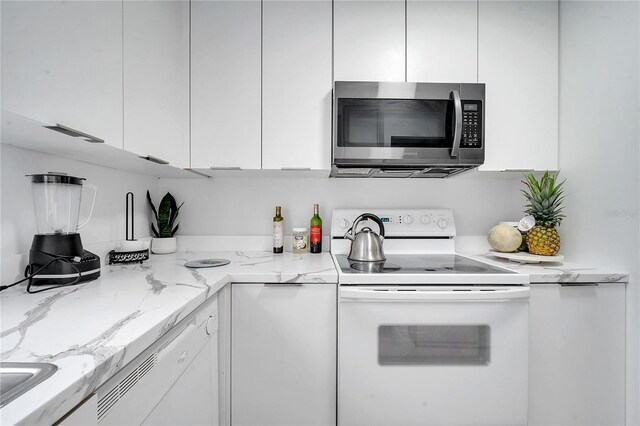 kitchen with white cabinetry, light stone countertops, and white appliances