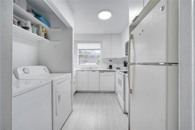 laundry room featuring washing machine and clothes dryer, sink, and light hardwood / wood-style flooring