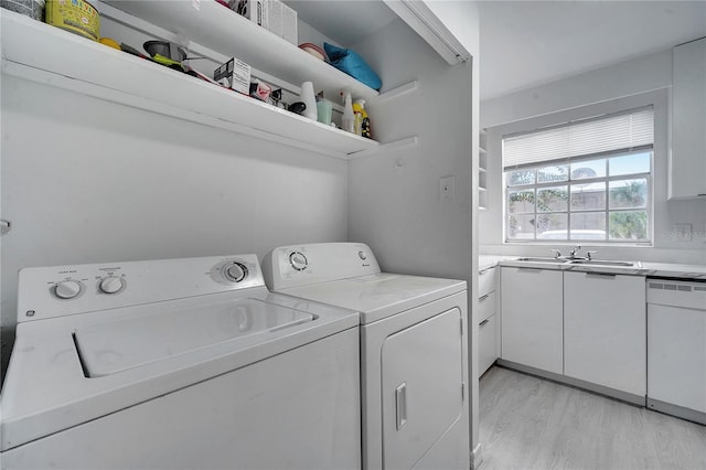 laundry room with separate washer and dryer, light wood-type flooring, and sink