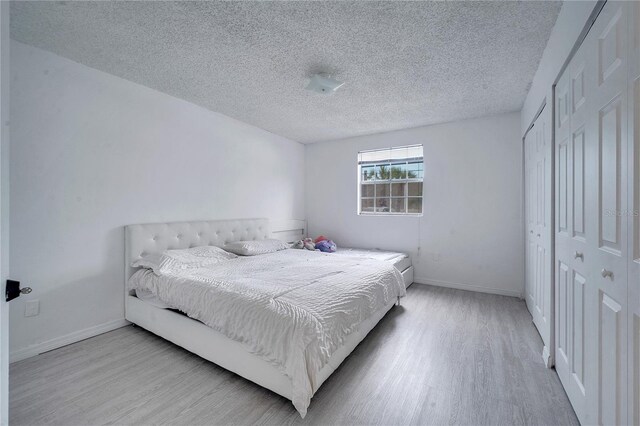 bedroom with light hardwood / wood-style floors, a closet, and a textured ceiling