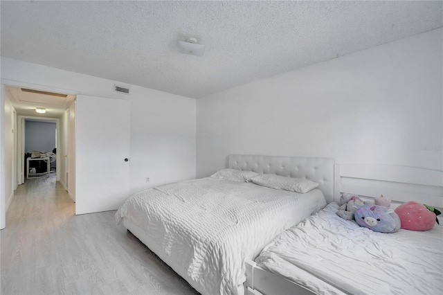 bedroom with light wood-type flooring and a textured ceiling