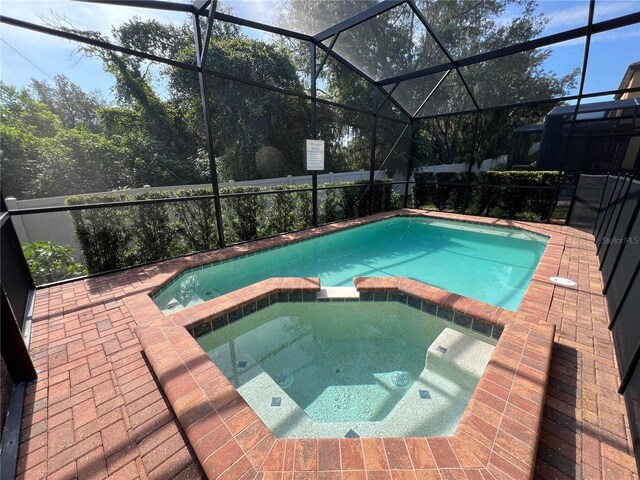 view of swimming pool featuring an in ground hot tub, a patio, and glass enclosure