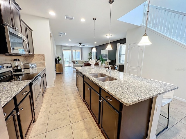 kitchen featuring dark brown cabinets, tasteful backsplash, light stone counters, ceiling fan, and stainless steel appliances