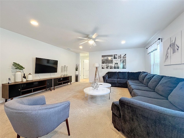 living room with ceiling fan, light carpet, and a textured ceiling