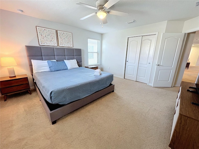 bedroom featuring light colored carpet, a closet, and ceiling fan