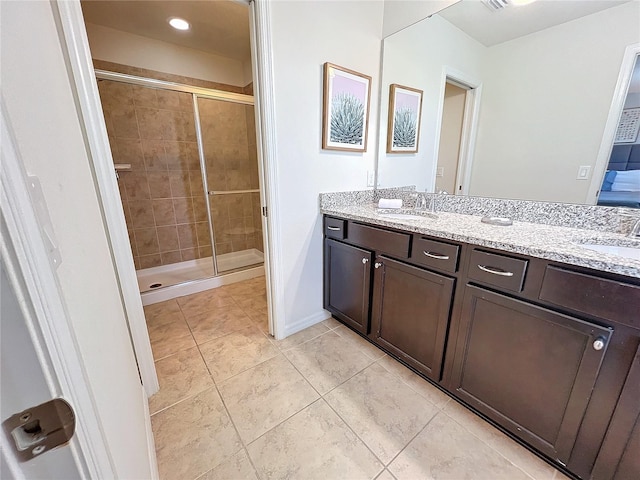 bathroom featuring a shower with shower door, tile patterned floors, and dual bowl vanity