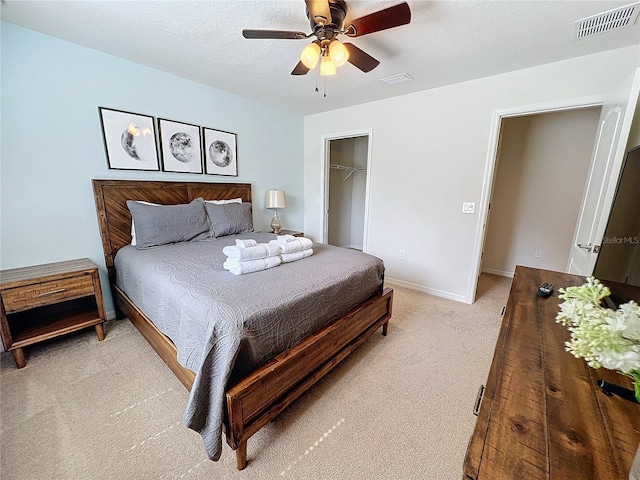 bedroom featuring a spacious closet, light carpet, a closet, and ceiling fan