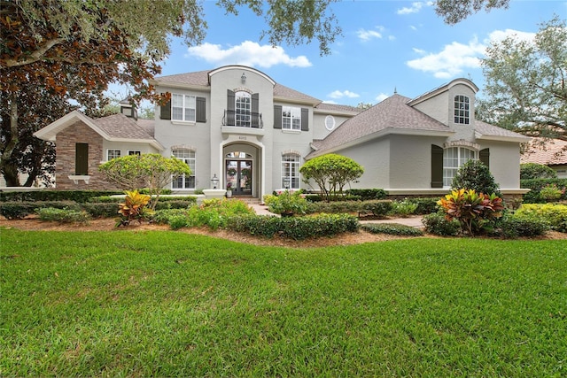 view of front of home featuring stucco siding, stone siding, a front lawn, and french doors