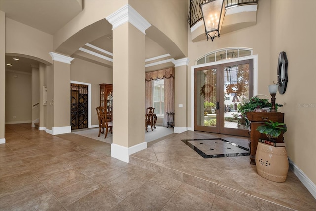 foyer with tile patterned floors, decorative columns, french doors, and a high ceiling