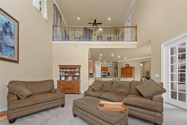 living room featuring arched walkways, recessed lighting, a towering ceiling, ornamental molding, and light carpet