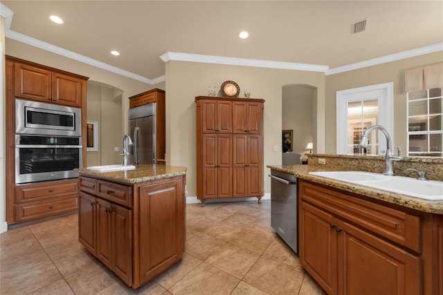 kitchen with a center island with sink, brown cabinetry, and built in appliances