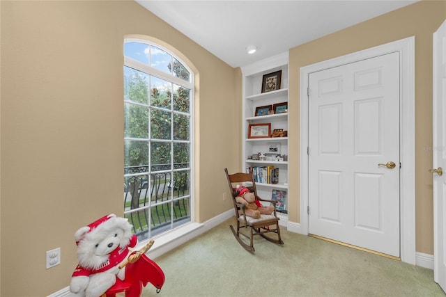 living area featuring built in features, light colored carpet, and baseboards