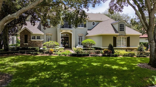 view of front facade with stone siding, a front yard, and stucco siding