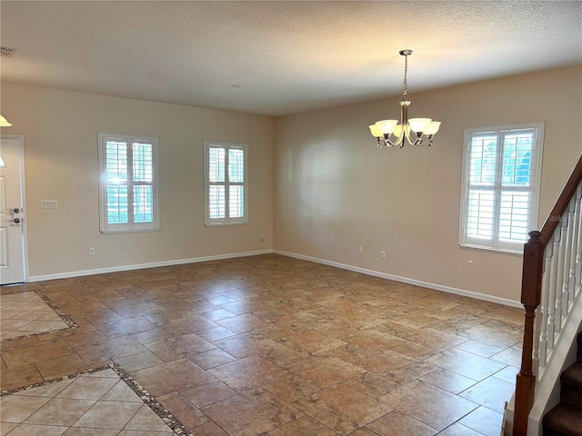 spare room with a textured ceiling and a chandelier