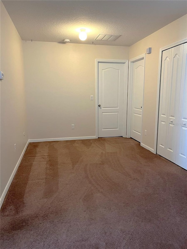 carpeted empty room with a textured ceiling