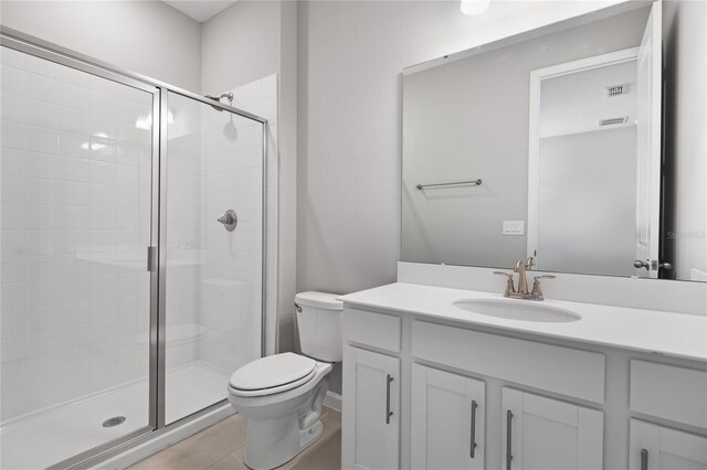 bathroom featuring tile patterned floors, toilet, an enclosed shower, and vanity