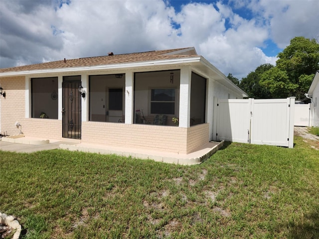 2518 Bowmer Dr, Kissimmee, FL 34744 - back of property featuring brick siding, a sunroom, a gate, and a shingled roof