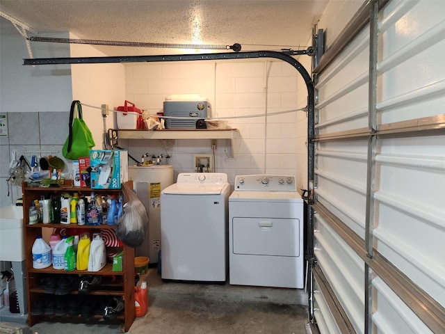 clothes washing area featuring electric water heater, washing machine and dryer, and a textured ceiling